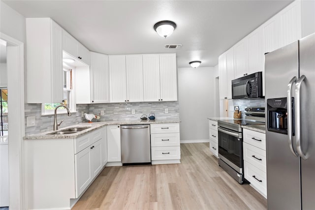 3532 Haltom Rd, Haltom City, TX 76117 - kitchen with stainless steel appliances, a sink, light wood-style floors, decorative backsplash, and white cabinets