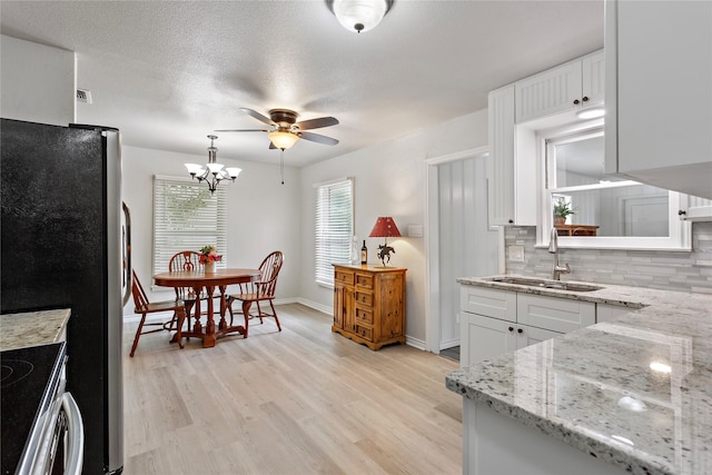 3532 Haltom Rd, Haltom City, TX 76117 - kitchen featuring a sink, ceiling fan, backsplash, white cabinetry, and light wood-style flooring