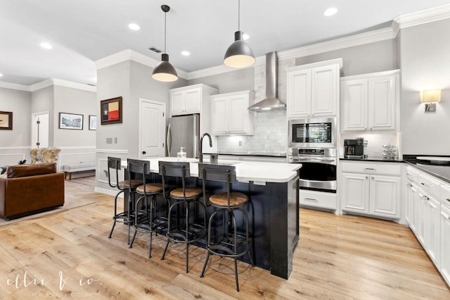 2409 Lynbrook Dr, Abilene, TX 79606 - kitchen with stainless steel appliances, wall chimney range hood, ornamental molding, a kitchen breakfast bar, and an island with sink