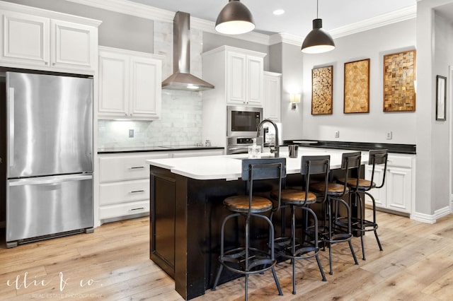 2409 Lynbrook Dr, Abilene, TX 79606 - kitchen featuring appliances with stainless steel finishes, wall chimney range hood, ornamental molding, white cabinetry, and tasteful backsplash
