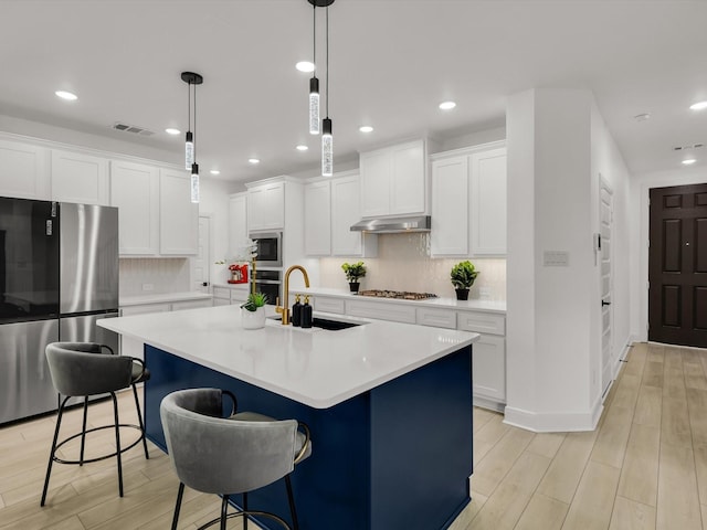 13333 Hedgebrook Pl, Fort Worth, TX 76008 - kitchen with appliances with stainless steel finishes, a sink, light wood finished floors, a center island with sink, and light countertops