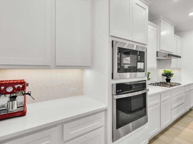 13333 Hedgebrook Pl, Fort Worth, TX 76008 - kitchen with stainless steel appliances, tasteful backsplash, under cabinet range hood, light countertops, and white cabinetry