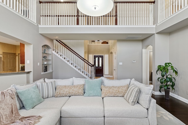 269 Love Bird Ln, Murphy, TX 75094 - living area featuring a towering ceiling, arched walkways, wood finished floors, baseboards, and stairs