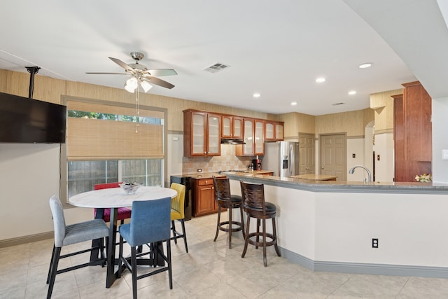269 Love Bird Ln, Murphy, TX 75094 - kitchen featuring stainless steel fridge, ceiling fan, glass insert cabinets, decorative backsplash, and a peninsula