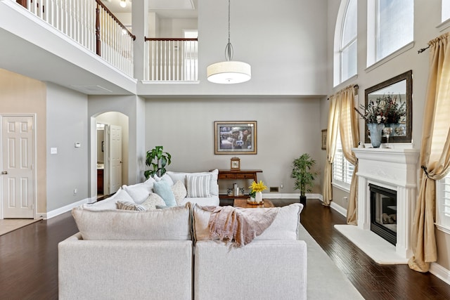 269 Love Bird Ln, Murphy, TX 75094 - living room with a towering ceiling, arched walkways, dark wood-style floors, baseboards, and a glass covered fireplace