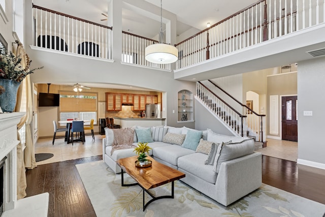 269 Love Bird Ln, Murphy, TX 75094 - living room with a ceiling fan, a towering ceiling, arched walkways, hardwood / wood-style flooring, and stairway