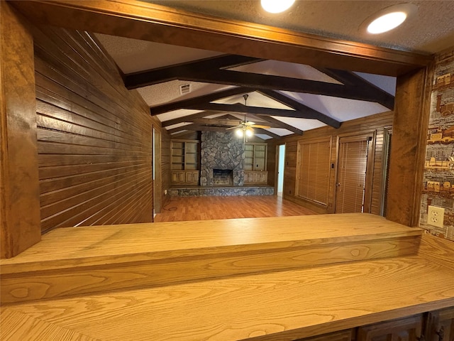327 Shadowwood Trl, Ovilla, TX 75154 - unfurnished living room featuring wood walls, a ceiling fan, a stone fireplace, and wood finished floors