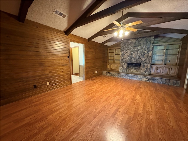 327 Shadowwood Trl, Ovilla, TX 75154 - unfurnished living room with wood walls, ceiling fan, wood finished floors, and a stone fireplace