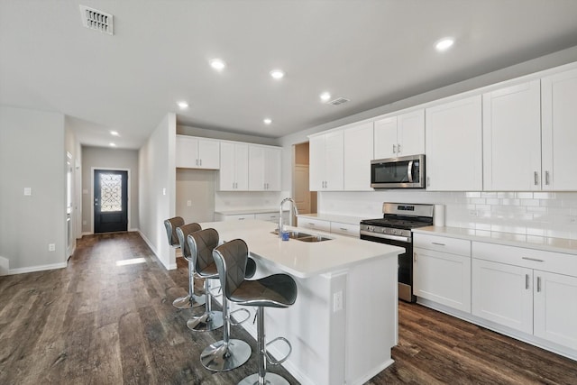 6112 Fire Water Dr, Fort Worth, TX 76179 - kitchen with stainless steel appliances, a sink, an island with sink, dark wood finished floors, and white cabinets