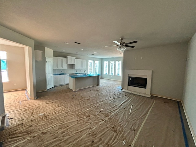 3514 Columbus St, Gainesville, TX 76240 - kitchen with white cabinets, ceiling fan, open floor plan, an island with sink, and baseboards