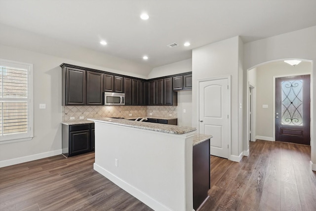 7802 Lindsey Dr, Rowlett, TX 75088 - kitchen with stainless steel microwave, arched walkways, a center island, backsplash, and dark wood finished floors