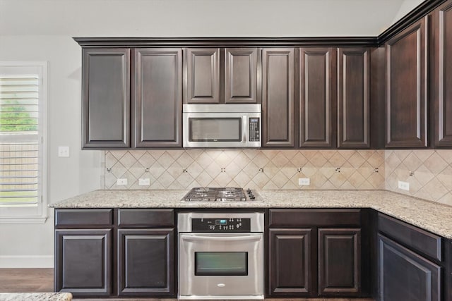 7802 Lindsey Dr, Rowlett, TX 75088 - kitchen featuring appliances with stainless steel finishes, dark brown cabinets, baseboards, decorative backsplash, and light stone counters