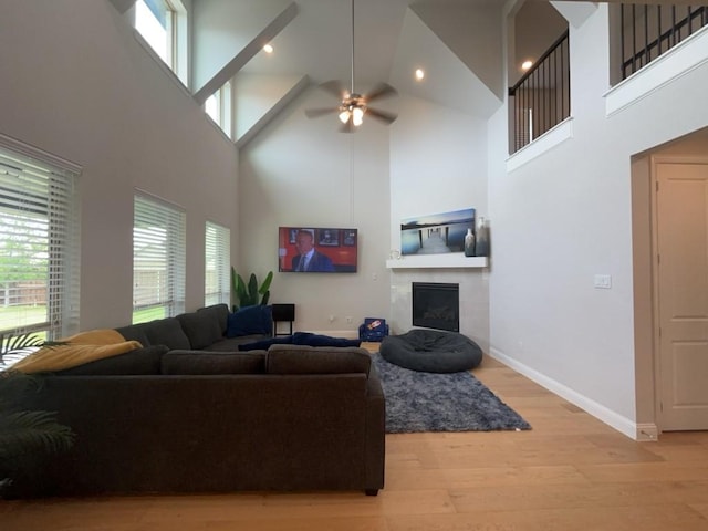 501 Upper Falls Ln, Mansfield, TX 76063 - living area with a towering ceiling, light wood-style floors, ceiling fan, a tiled fireplace, and baseboards