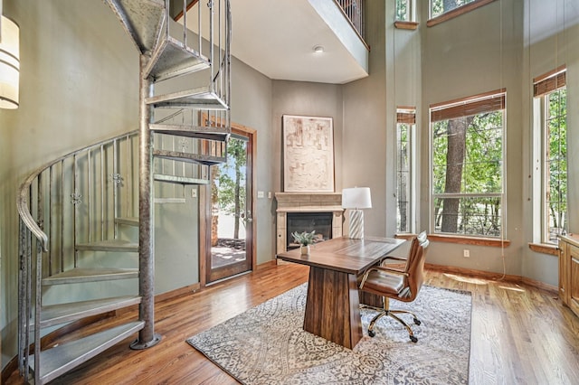 1 Hamper Ct, Trophy Club, TX 76262 - office featuring a towering ceiling, a glass covered fireplace, wood finished floors, and baseboards