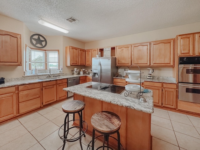 1665 Fm 2452, Corsicana, TX 75110 - kitchen with stainless steel appliances, a sink, a breakfast bar area, a textured ceiling, and a center island