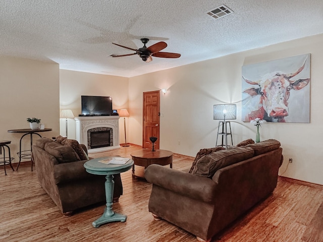 1665 Fm 2452, Corsicana, TX 75110 - living room with wood finished floors, ceiling fan, a glass covered fireplace, a textured ceiling, and baseboards