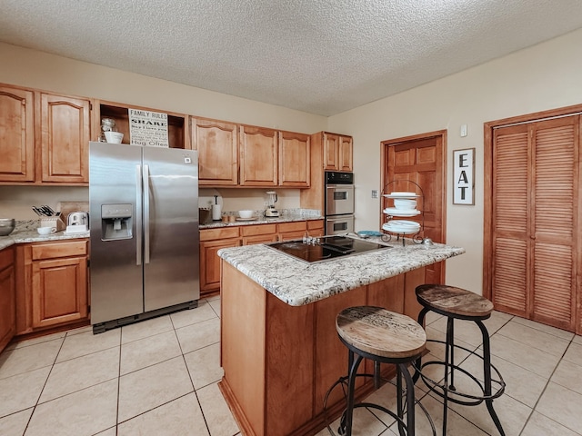 1665 Fm 2452, Corsicana, TX 75110 - kitchen with stainless steel appliances, light tile patterned flooring, a breakfast bar, a textured ceiling, and a kitchen island
