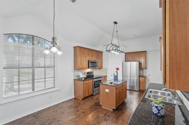 7602 Bridge Water Cir, Frisco, TX 75034 - kitchen featuring appliances with stainless steel finishes, a sink, vaulted ceiling, a center island, and tasteful backsplash