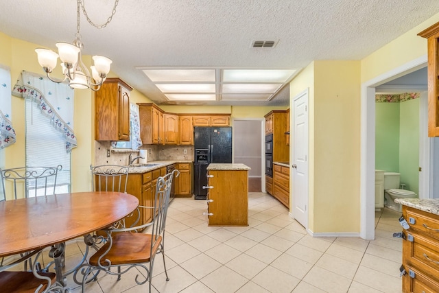 2816 Wateridge Ct, Grapevine, TX 76051 - kitchen with black appliances, a sink, a kitchen island, a chandelier, and brown cabinetry