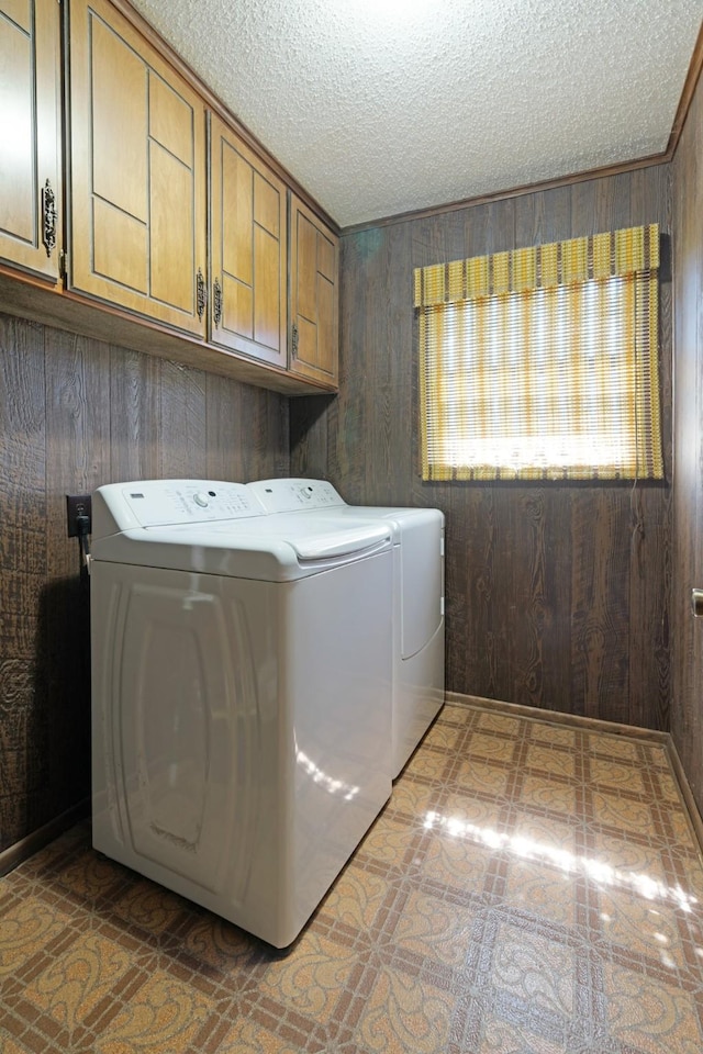 905 W 11th, Clarksville, TX 75426 - laundry area featuring cabinet space, independent washer and dryer, a textured ceiling, and wooden walls
