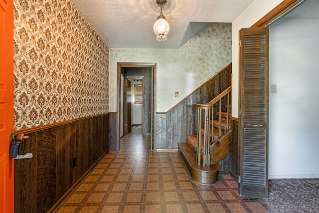905 W 11th, Clarksville, TX 75426 - entrance foyer with a wainscoted wall, wallpapered walls, a textured ceiling, stairs, and tile patterned floors