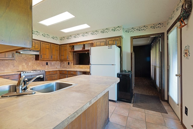 905 W 11th, Clarksville, TX 75426 - kitchen featuring freestanding refrigerator, light countertops, tasteful backsplash, range with electric cooktop, and under cabinet range hood