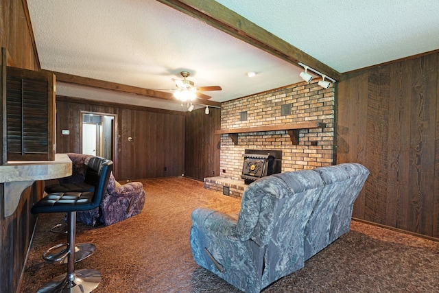 905 W 11th, Clarksville, TX 75426 - living room featuring wooden walls, carpet flooring, a textured ceiling, a wood stove, and ceiling fan