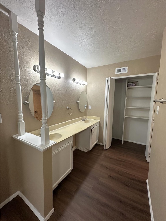 4629 Chapman St, The Colony, TX 75056 - full bathroom with wood finished floors, a textured ceiling, baseboards, double vanity, and a textured wall
