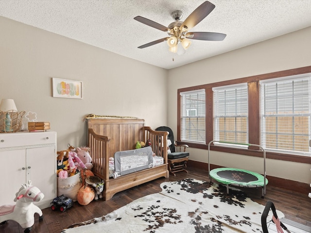 202 S Wood St, Cleburne, TX 76033 - bedroom with wood finished floors, a crib, a textured ceiling, ceiling fan, and baseboards