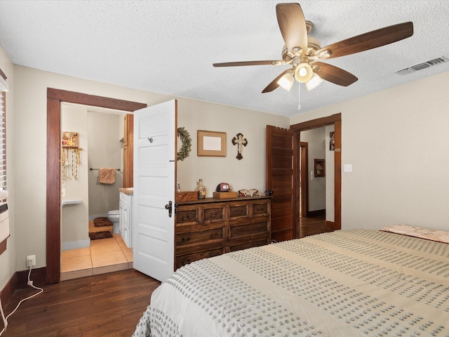 202 S Wood St, Cleburne, TX 76033 - bedroom featuring dark wood finished floors, a textured ceiling, ceiling fan, baseboards, and ensuite bath