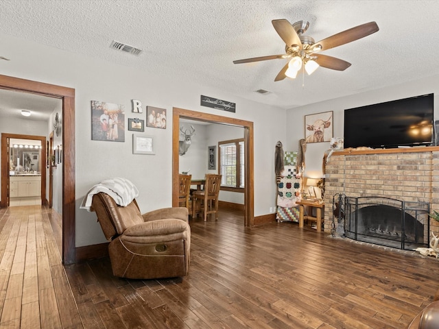202 S Wood St, Cleburne, TX 76033 - living area with ceiling fan, a textured ceiling, hardwood / wood-style floors, baseboards, and a fireplace