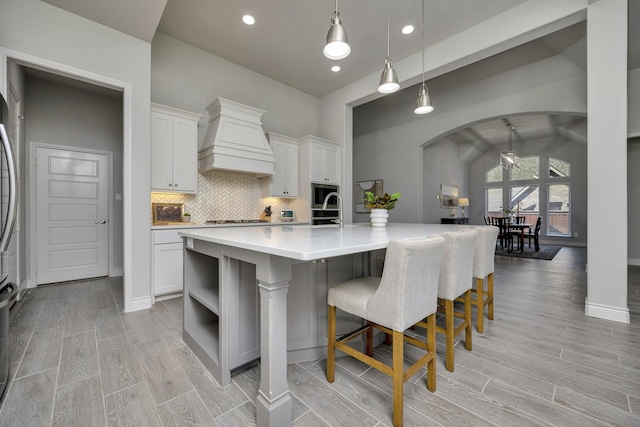 1008 Myers Park Trl, Roanoke, TX 76262 - kitchen featuring custom exhaust hood, arched walkways, light countertops, open shelves, and light wood finished floors