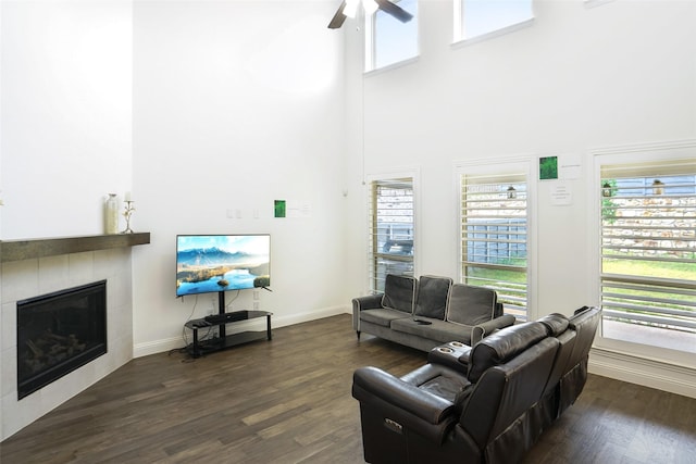 616 Evergreen Rd, Little Elm, TX 76227 - living area featuring ceiling fan, a tiled fireplace, dark wood-type flooring, a towering ceiling, and healthy amount of natural light
