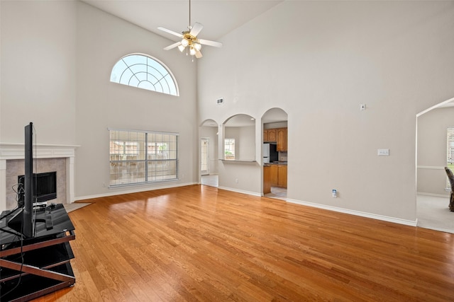 1117 Ruby St, Plano, TX 75094 - unfurnished living room featuring arched walkways, ceiling fan, light wood finished floors, a fireplace, and high vaulted ceiling