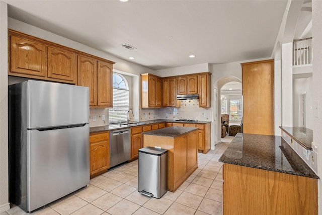 1117 Ruby St, Plano, TX 75094 - kitchen featuring appliances with stainless steel finishes, arched walkways, a sink, decorative backsplash, and dark stone countertops