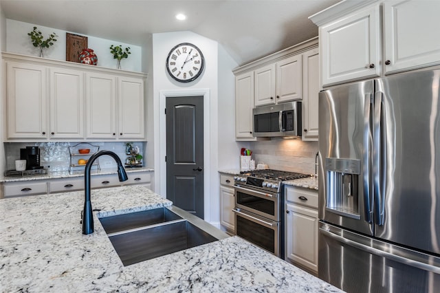 1719 Wheatberry Ln, Allen, TX 75002 - kitchen with stainless steel appliances, a sink, lofted ceiling, decorative backsplash, and light stone counters