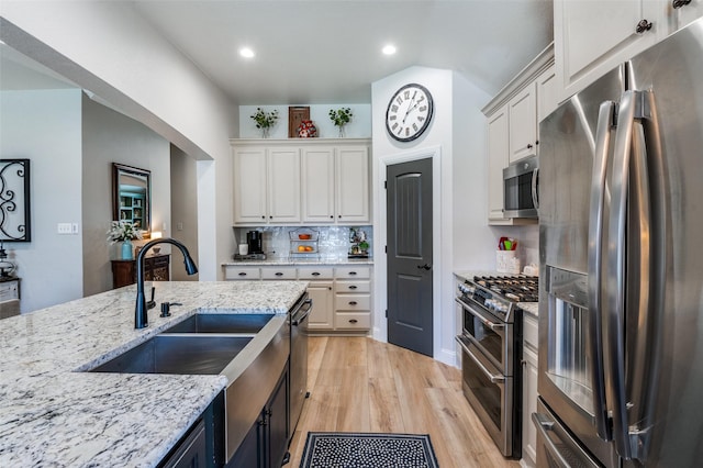 1719 Wheatberry Ln, Allen, TX 75002 - kitchen with stainless steel appliances, light wood-style flooring, white cabinetry, light stone counters, and a sink