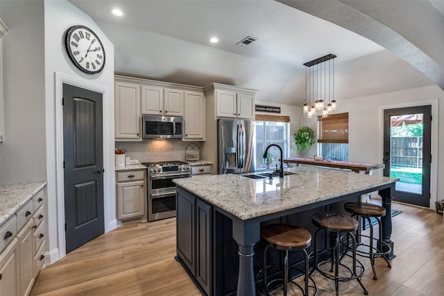1719 Wheatberry Ln, Allen, TX 75002 - kitchen with appliances with stainless steel finishes, a sink, light wood-style floors, a kitchen breakfast bar, and an island with sink