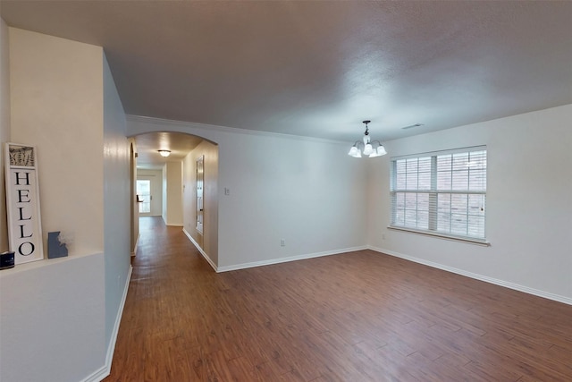 637 Stirrup Bar Dr, Fort Worth, TX 76179 - spare room featuring arched walkways, a chandelier, dark wood-type flooring, baseboards, and crown molding