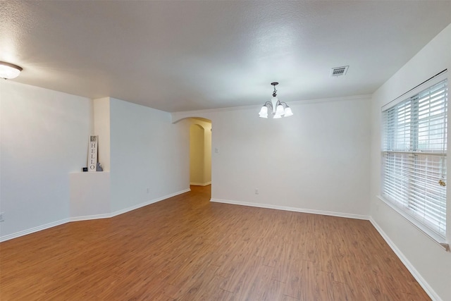 637 Stirrup Bar Dr, Fort Worth, TX 76179 - spare room with a chandelier, wood finished floors, arched walkways, baseboards, and a textured ceiling