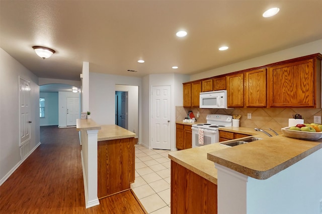 637 Stirrup Bar Dr, Fort Worth, TX 76179 - kitchen featuring white appliances, a sink, a peninsula, brown cabinetry, and light countertops