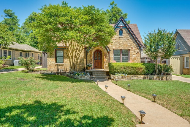 5447 Mccommas Blvd, Dallas, TX 75206 - tudor house featuring a front yard, stone siding, brick siding, and central AC unit