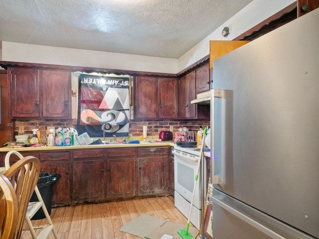 102 Ford Cir, Gun Barrel City, TX 75156 - kitchen featuring freestanding refrigerator, electric range, light wood-type flooring, under cabinet range hood, and a textured ceiling
