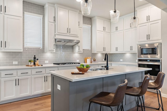 17120 Lacebark Ln, Dallas, TX 75252 - kitchen featuring stainless steel appliances, light wood-style floors, a kitchen breakfast bar, and white cabinets