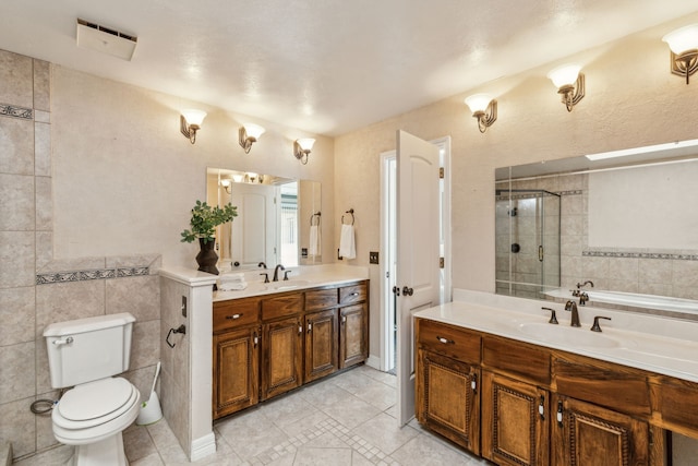 3109 Bullock Dr, Plano, TX 75023 - full bathroom featuring tile patterned floors, a stall shower, toilet, two vanities, and tile walls