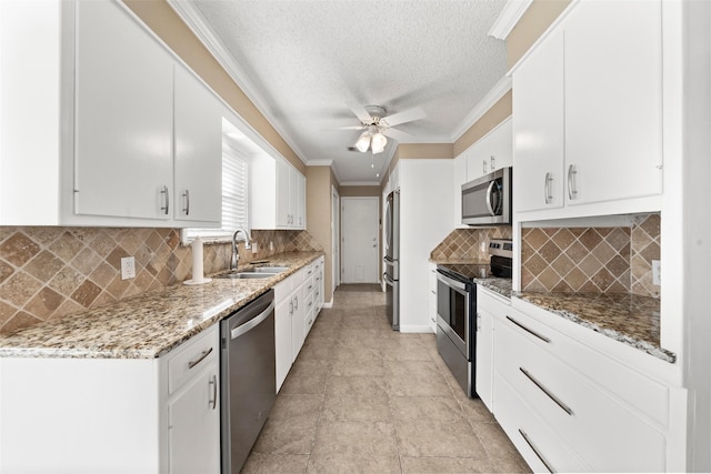 4201 Westchester Dr, Waco, TX 76710 - kitchen featuring stainless steel appliances, a sink, ornamental molding, white cabinetry, and a ceiling fan