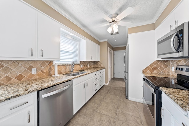 4201 Westchester Dr, Waco, TX 76710 - kitchen featuring appliances with stainless steel finishes, a sink, white cabinetry, crown molding, and ceiling fan