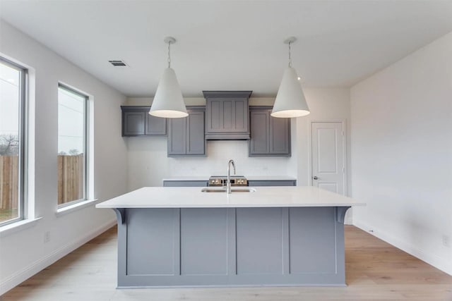 2316 Glasgow Way, Denton, TX 76207 - kitchen featuring a sink, light countertops, decorative backsplash, an island with sink, and light wood-style floors