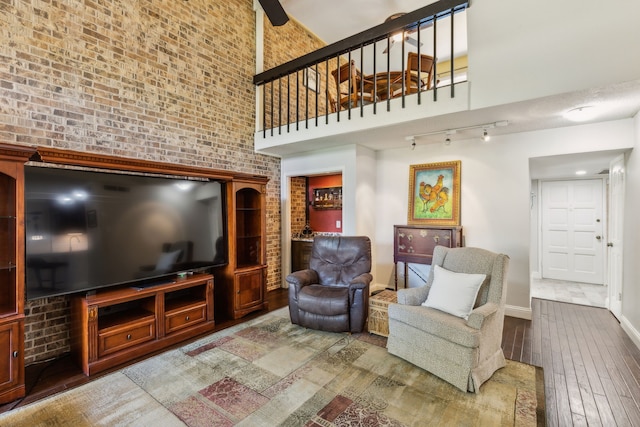 2902 Shady Lake Cir, Carrollton, TX 75006 - living room with hardwood / wood-style flooring, a towering ceiling, brick wall, baseboards, and rail lighting