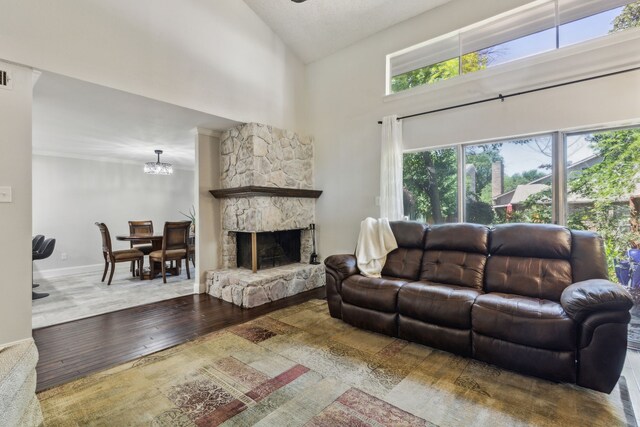 2902 Shady Lake Cir, Carrollton, TX 75006 - living room with a high ceiling, a stone fireplace, wood-type flooring, a chandelier, and baseboards